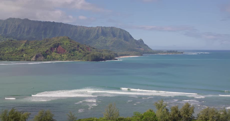 Coastline at midday with a resort nestled among trees overlooking a wide open ocean view in the background