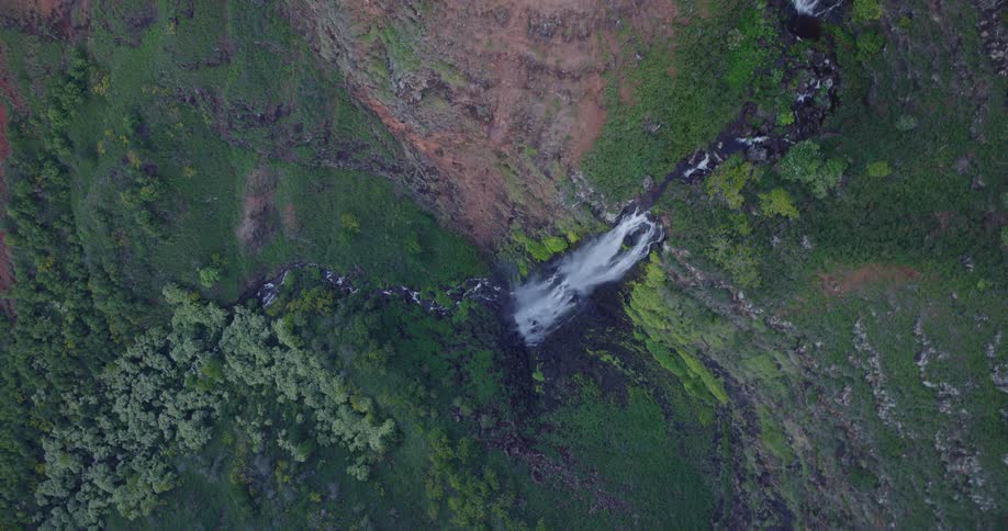 A very tall cliff has a waterfall cascading down the side of it