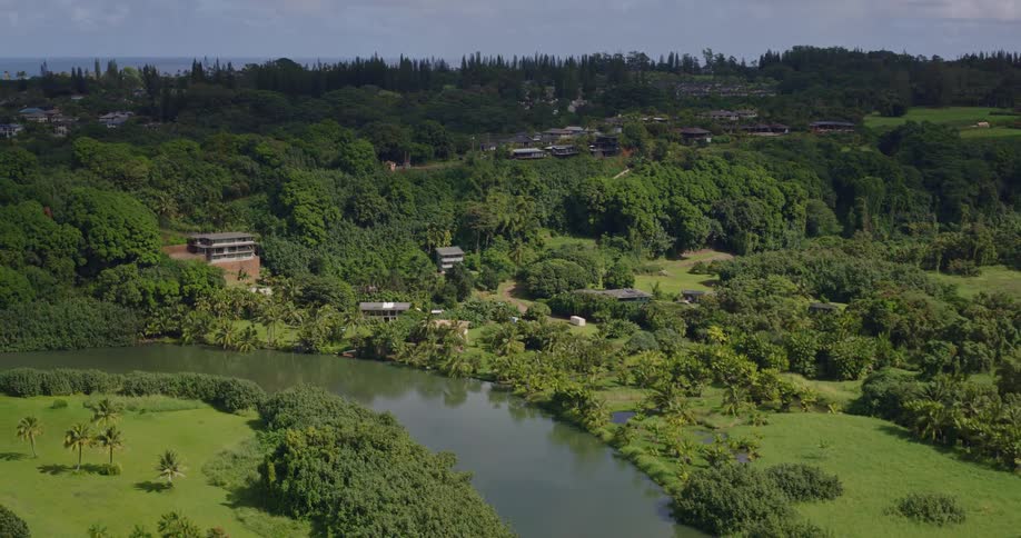 Aerial view of a rural area with a winding river green fields and scattered residences among trees
