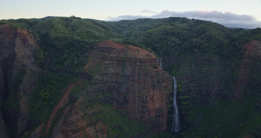 A tall narrow waterfall plunges down a mountain cliff side