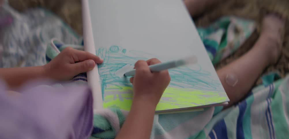 Little girl drawing while sitting on the beach sand