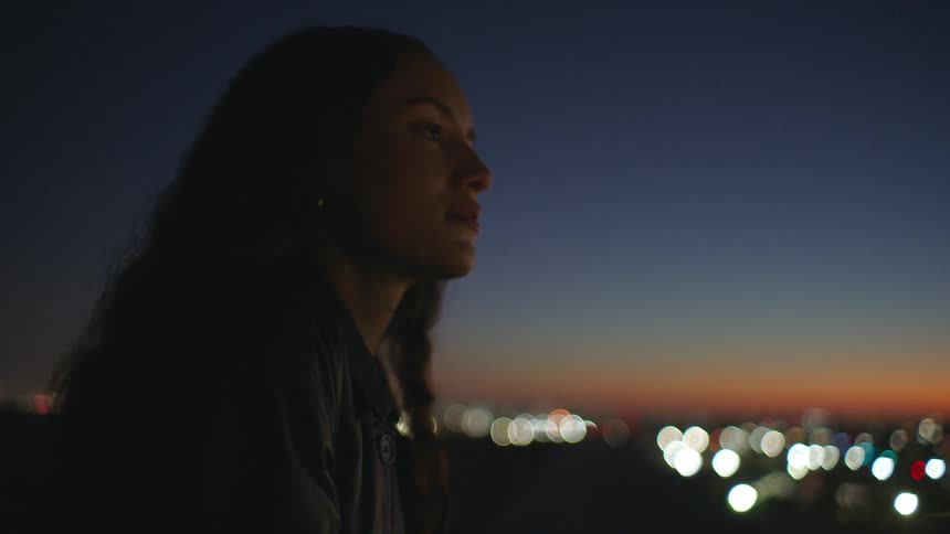 A woman standing outdoors at dusk