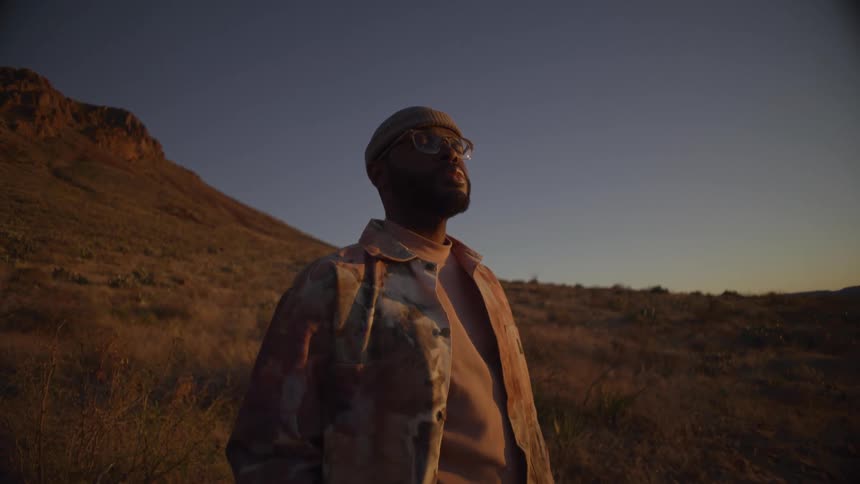 The man is standing in front of the mountain