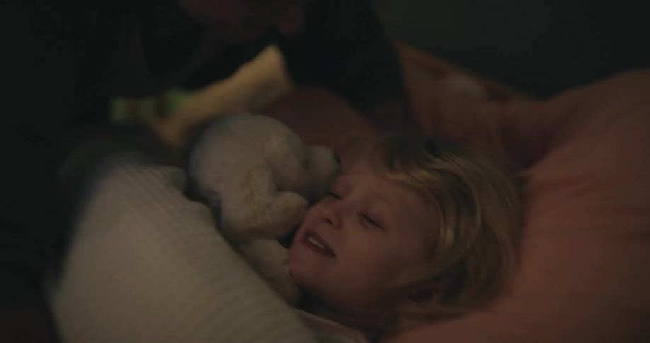 A mother tucking her daughter in to bed