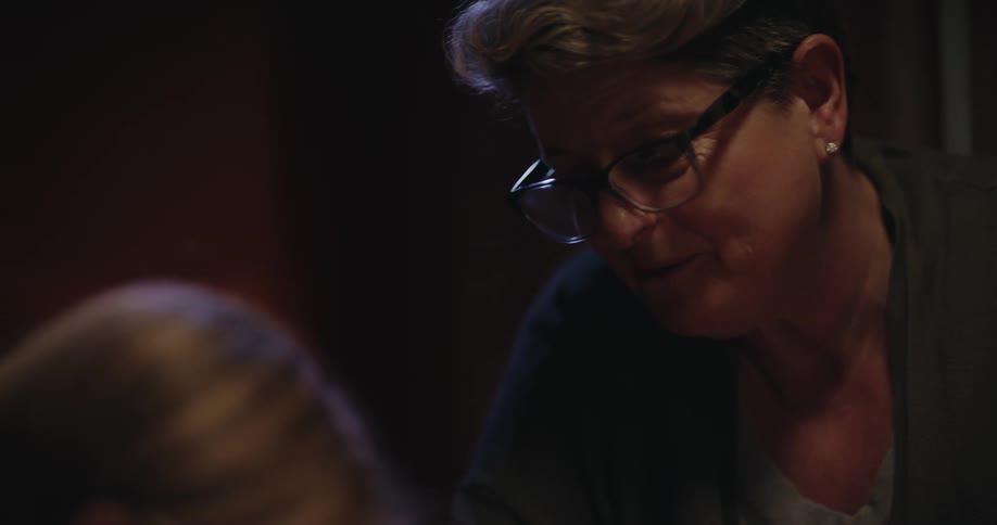 The mother talks with her daughter as she studies