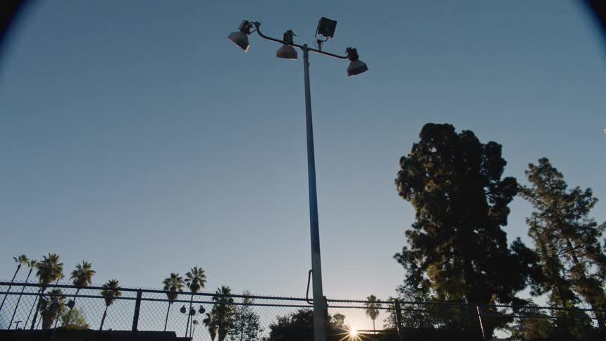 The sun is shining on the lamp post in the park