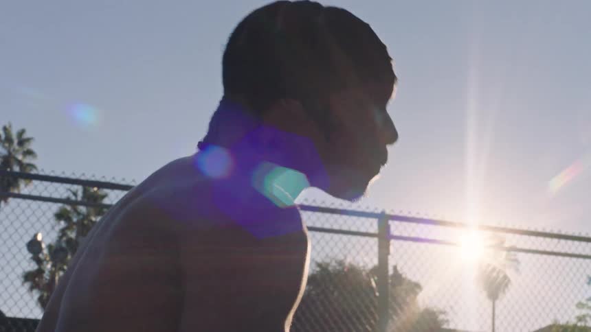Young adult black man on a sports court shooting a basketball outdoors during day time