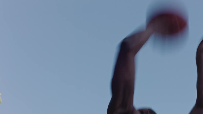 In the video a persons arm enters the frame from the bottom and reaches upward toward a clear blue sky the hand is closed into a fist creating a silhouette against the bright open background before lowering back out of view
