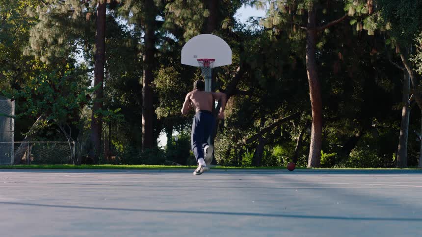 The man is running back and forth on the basketball court