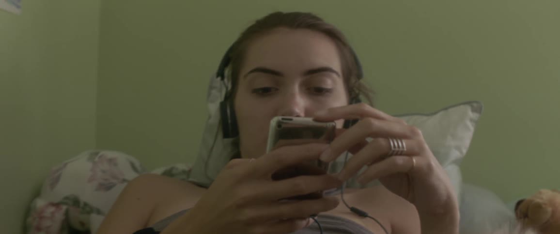 A woman wears headphones in bed