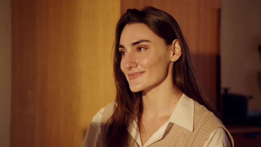 Woman alone indoors smiles while thinking