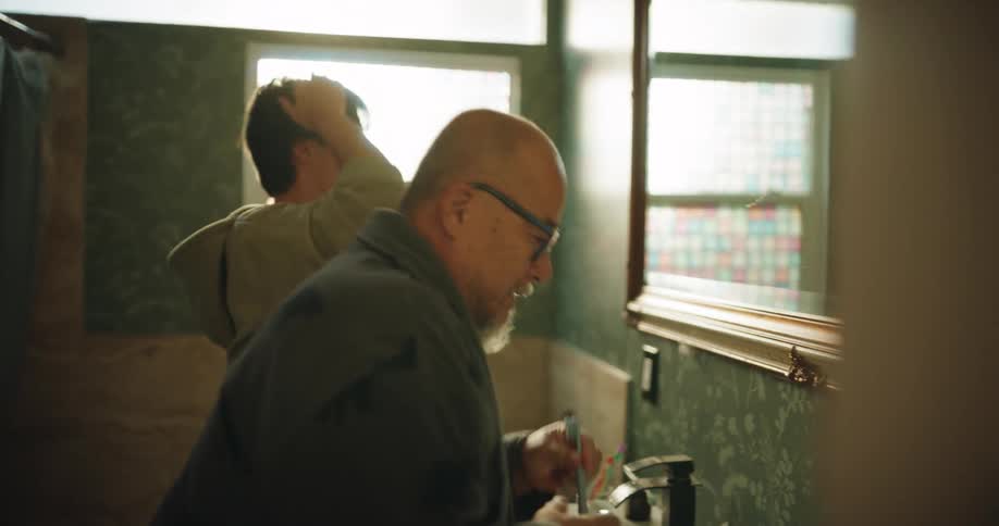Two people brushing teeth in a bathroom
