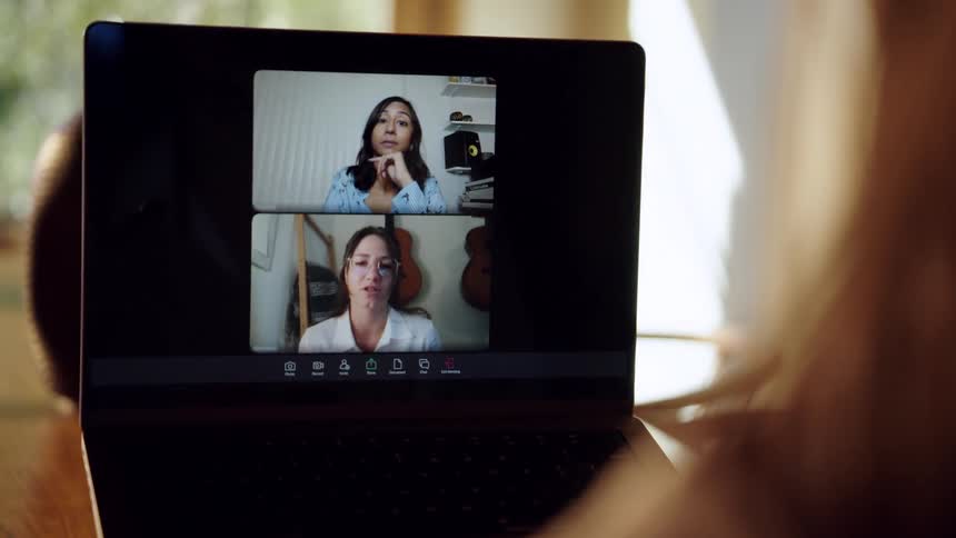 Woman participates in a video conference with two other women during the daytime
