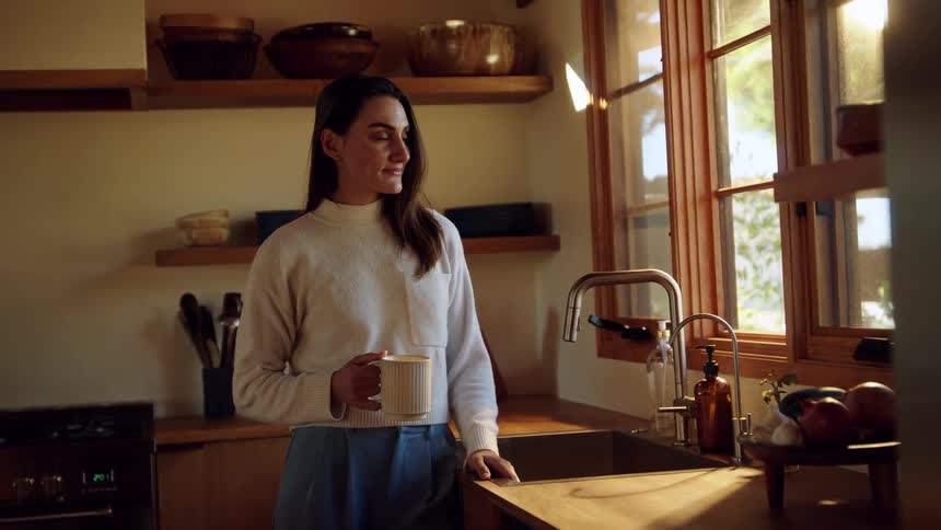 A woman standing in a kitchen looking out a window