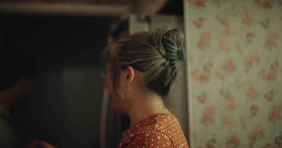 The woman is smiling and talking with someone who walks away