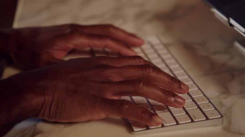A persons hands typing on a keyboard