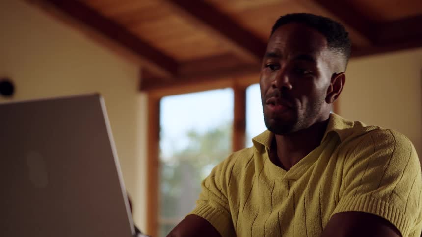 Man sitting at a table having a conversation on a laptop computer