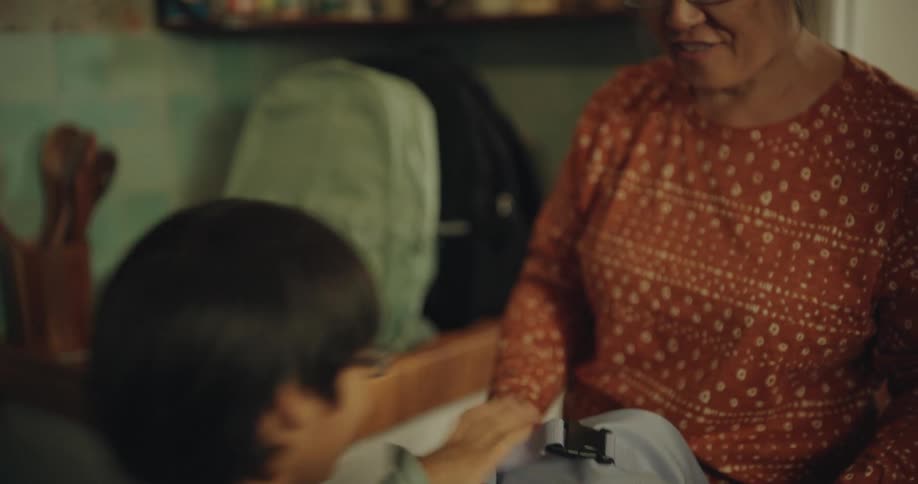 Woman hands backpacks to each of her children as they leave for school