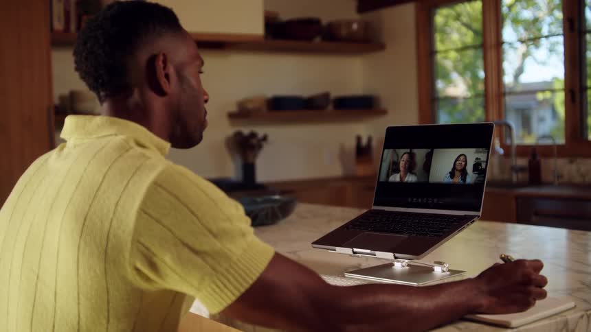 During a video call a man writes on his notepad