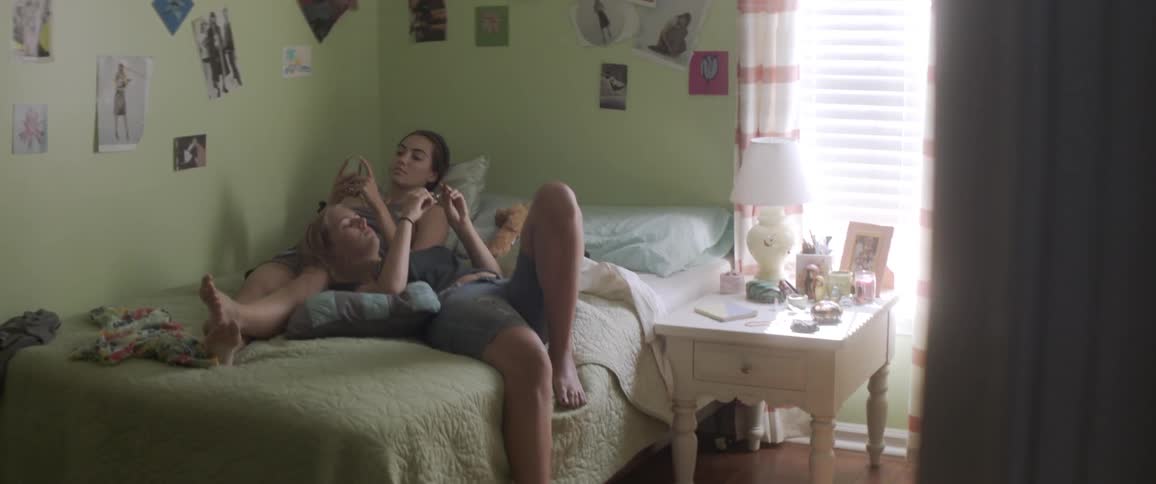 Two girls sit on a bed together