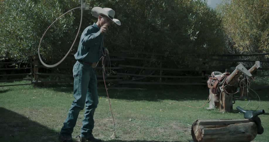 Cowboy throwing a lasso at a practice target in an outdoor grassy area