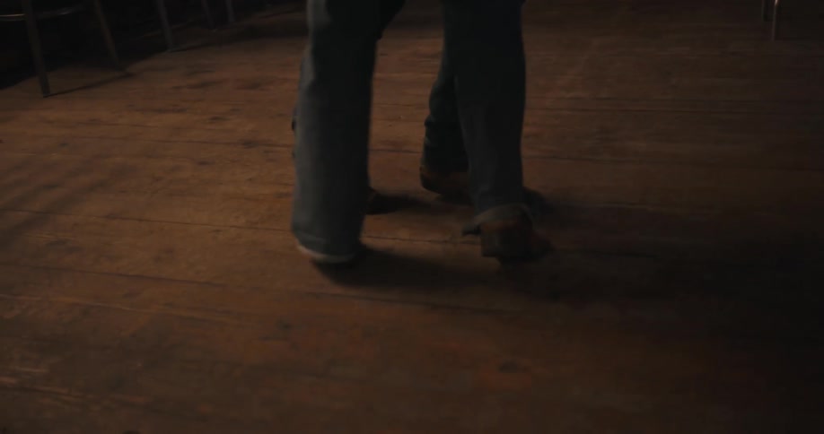 Peoples feet dance on a wooden floor in an indoor setting