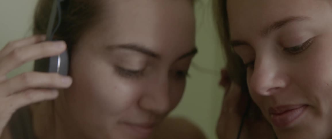 Woman smiling and sharing her headphones with another woman