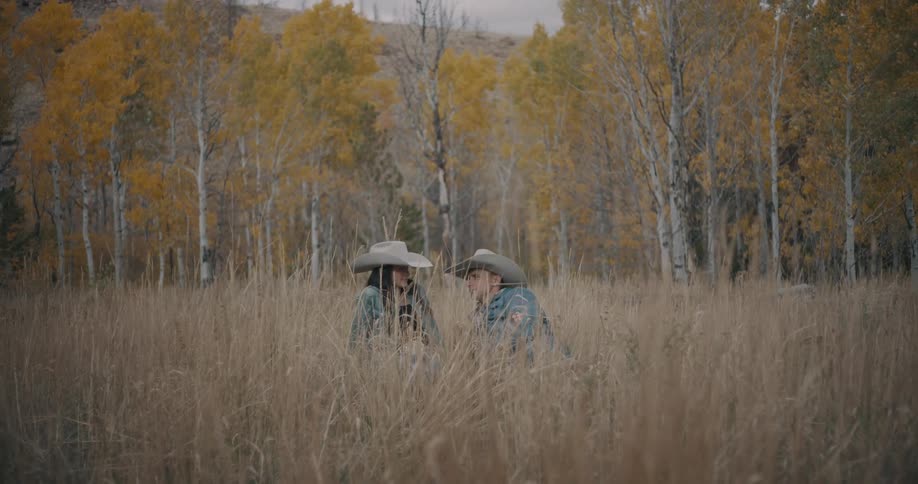 Man and woman sitting in tall grass in a rural field