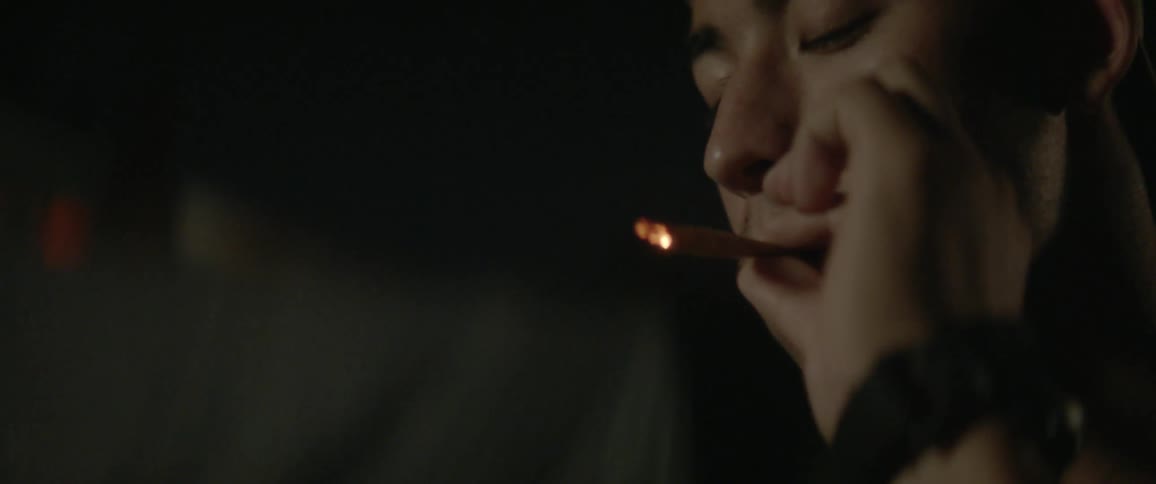 A woman smokes a cigarette and passes it to a man