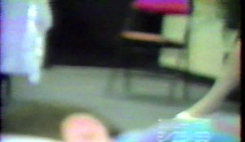 Boy smiles and shields his face while waiting with others in a waiting room