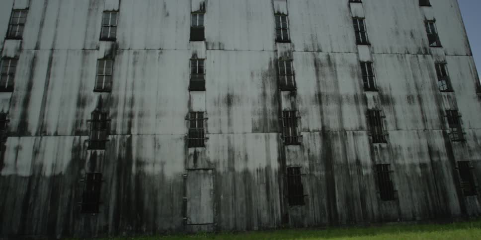 A big old building with many windows on a sunny day with green grass and trees