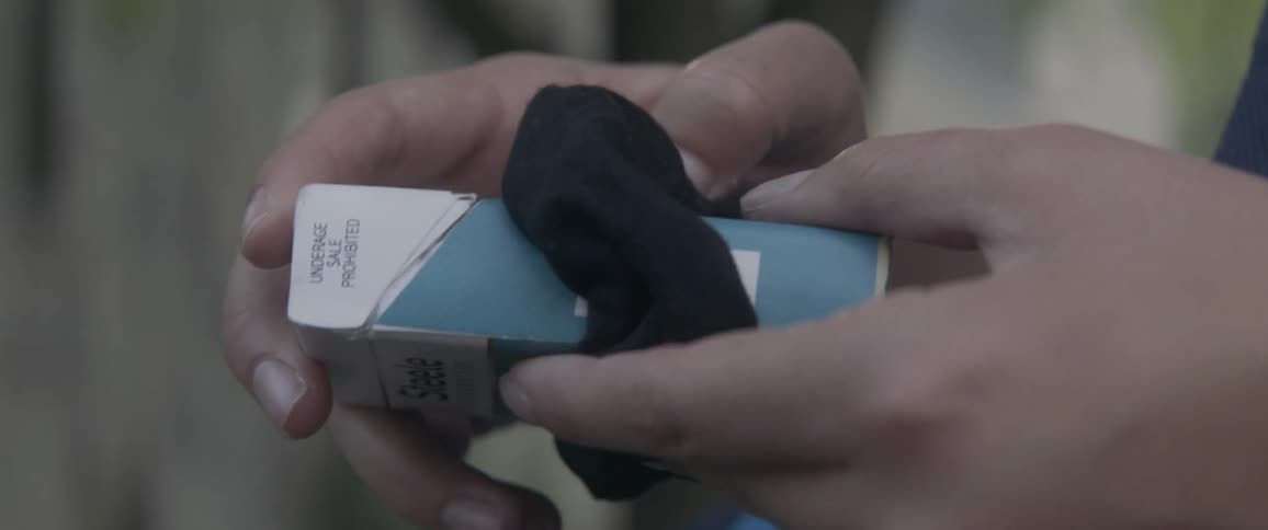 A person is holding a pack of cigarettes