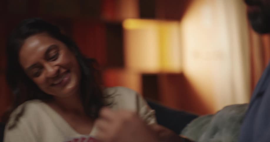 Man feeds a woman and then kisses her while they play cards