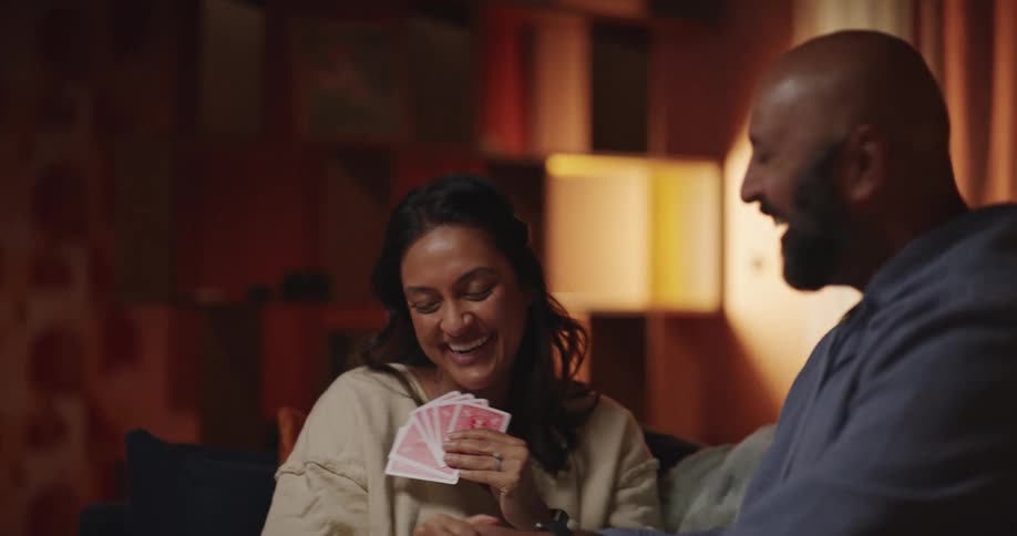 Woman and a man are smiling playing cards together