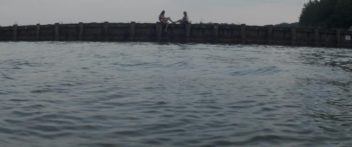 Two people sit on the pier on a windy day