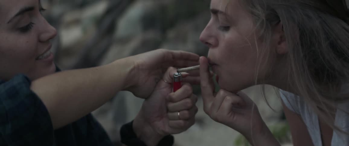 A woman leans forward to have her smoke lit