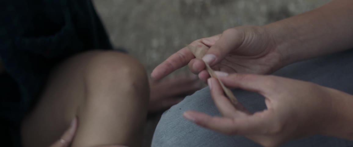 A person is rolling a joint with a friend