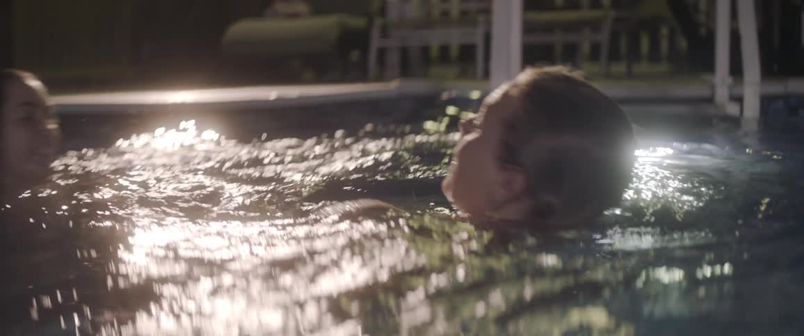 Two women splash in a swimming pool
