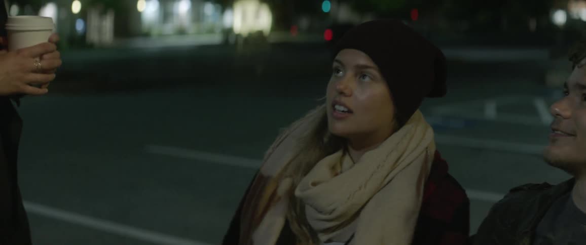 Man and woman stand in a parking lot at night talking