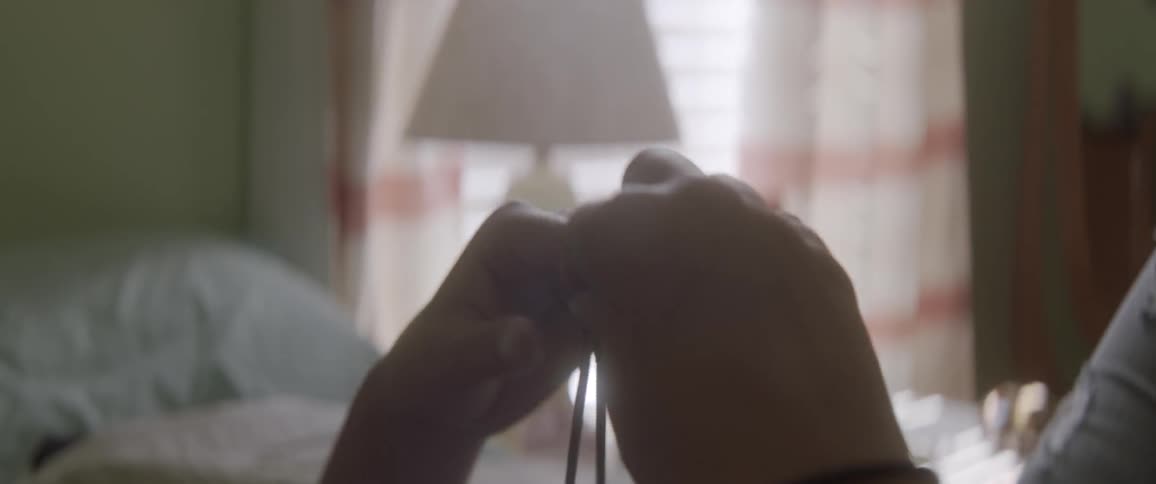 Person twirls a bracelet around in their hands in a bedroom