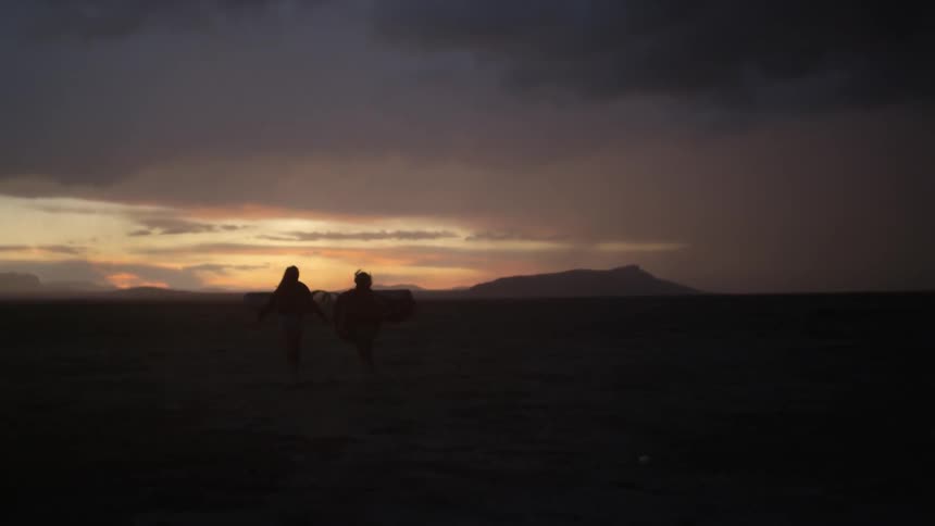 Two people run down a field at dawn