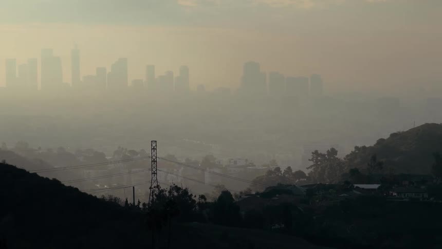 Metropolitan area next to hills covered in smog outdoors during dusk or dawn