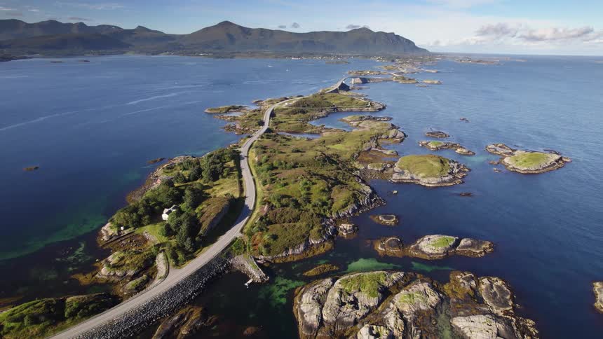 A car is moving along a highway that is bridges between islands toward a small coastal town in the mountains