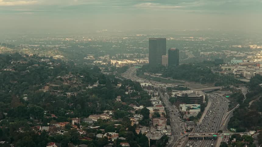 The camera is moving towards the city with the roads and cars below