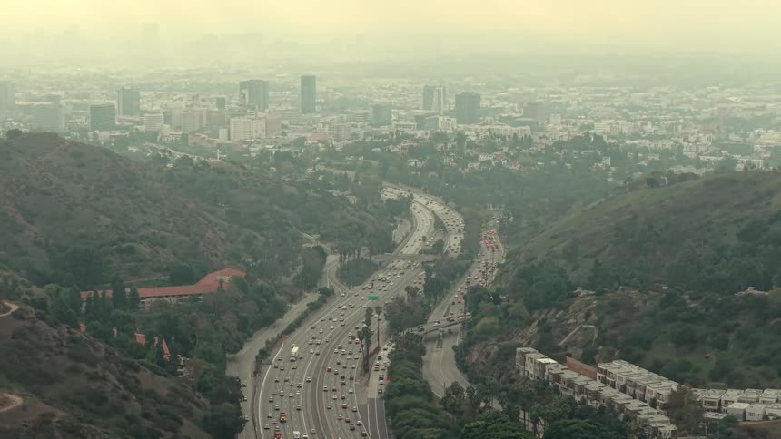 Winding highway cutting through urban area between hills