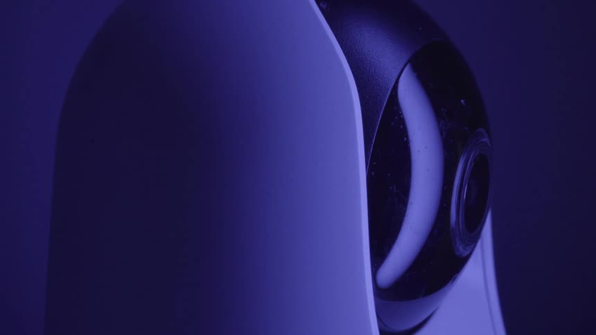 Security camera with rounded design under bluish lighting