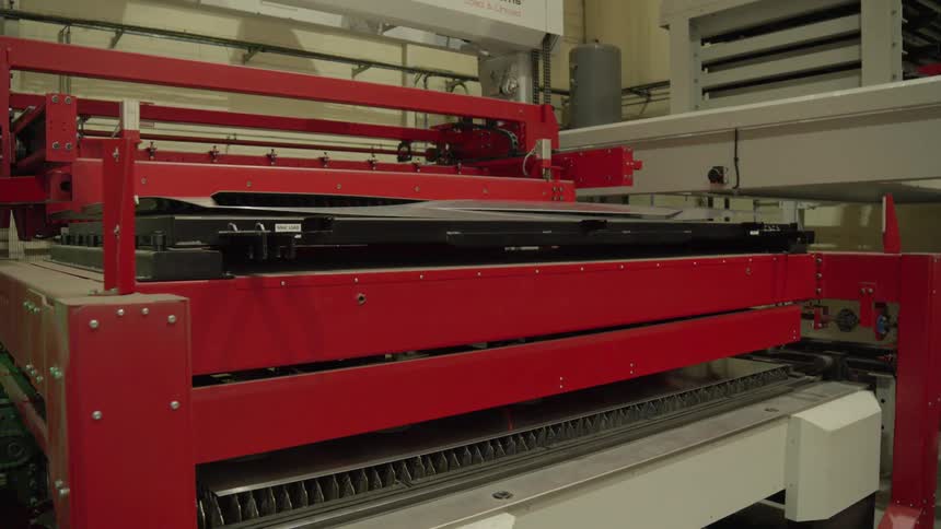 The red machine made of metal is moving back and forth and pressing down