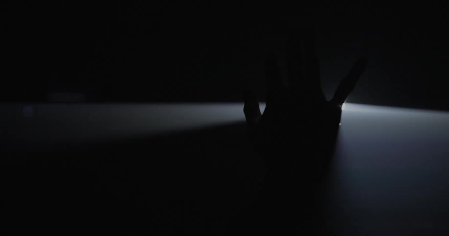 A person sticks their hand through a light projection