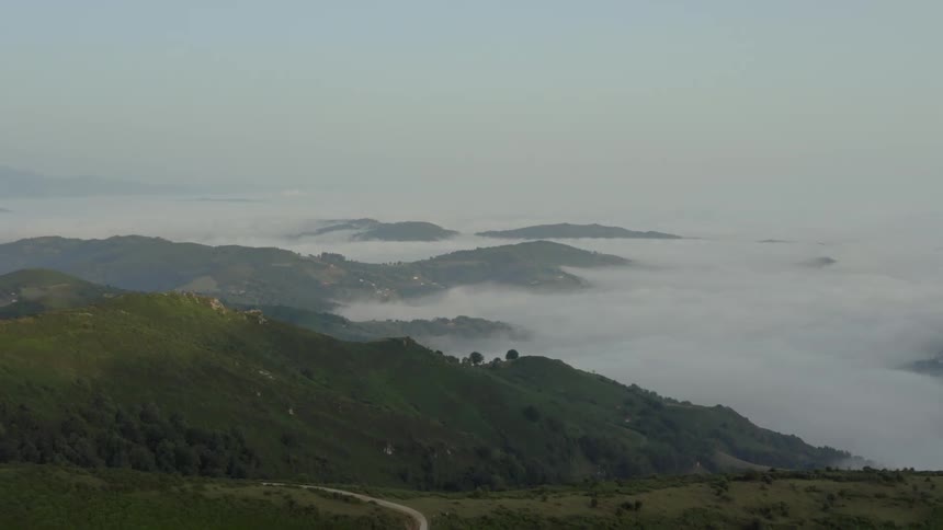 Natural landscape of an area with mountains and valleys partially covered in a dense mist outdoors during day time