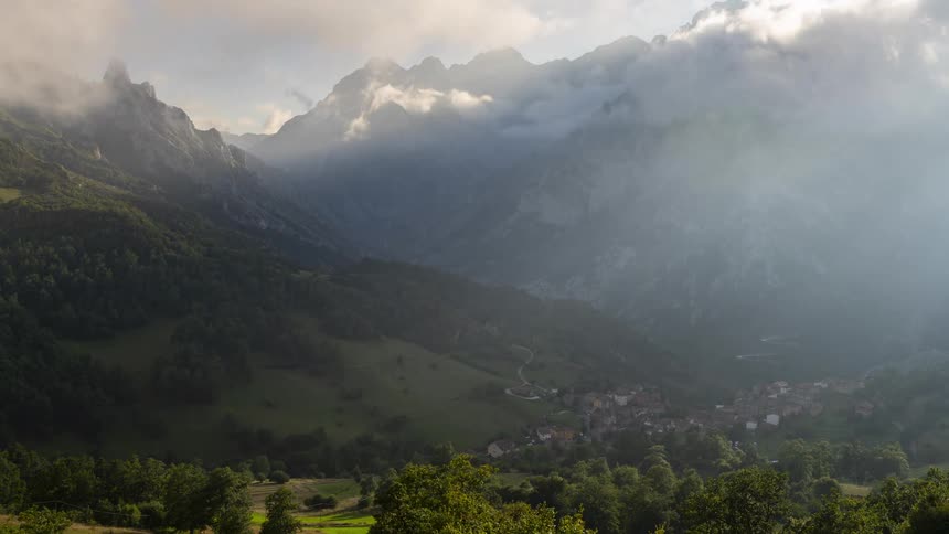 Houses and a small community in the mountain valley as clouds move across the sky